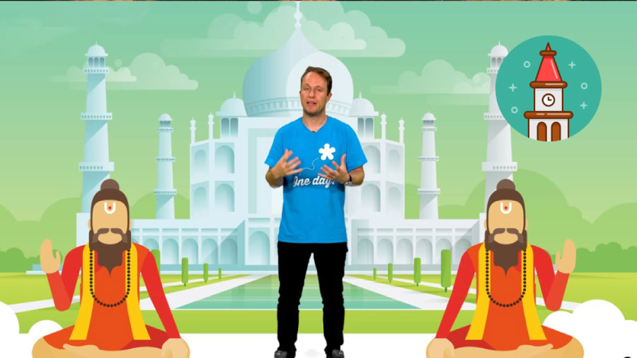 A man stands in front of a cartoon Taj Mahal with two Hindu figurines either side of him. His hands are raised and mouth open as if mid-conversation.